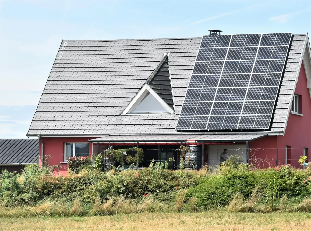 Maison rouge équipée de panneaux solaires sur son toit